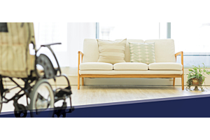 Un fauteuil roulant et un canapé dans un espace commun d'un établissement de soins de longue durée.