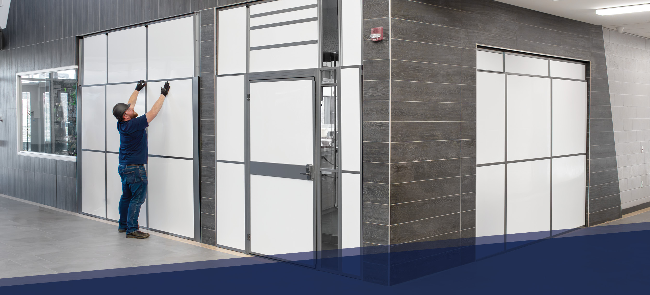Technician installing modular wall panels in a commercial building interior using a containment barrier system. Ideal for infection control, healthcare construction, or cleanroom environments requiring temporary wall systems for dust and particle containm